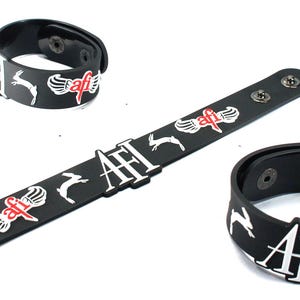 May include: Three black silicone wristbands featuring white rabbit silhouettes and the red and white AFI logo with wings. Each band includes metallic snap button closures for fastening, with one band shown flat and two shown in a circular shape.