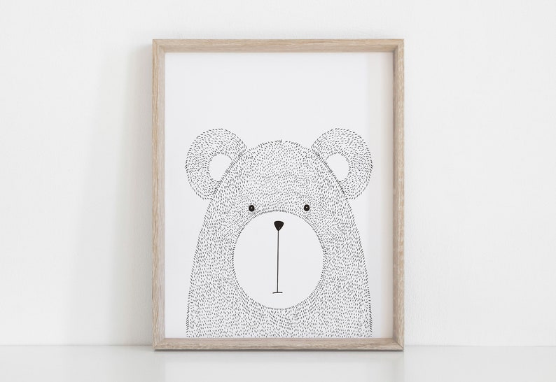 May include: A framed art print featuring a black and white illustration of a bear's face. The bear is drawn with a dotted texture, and the artwork is set within a light brown wooden frame. The bear has a simple, minimalist design.
