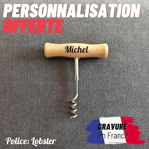Könnte beinhalten: Ein hölzerner Korkenzieher mit dem Namen "Michel" auf dem Griff graviert. Der Text "PERSONNALISATION OFFERTE" steht oben und "GRAVURE en France" unten, mit einer französischen Flagge.
