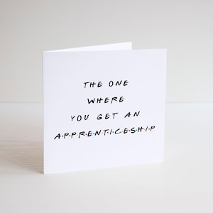May include: A folded white greeting card featuring the text "THE ONE WHERE YOU GET AN APPRENTICESHIP" in black. The word "APPRENTICESHIP" is in colorful letters. The card is on a white background.