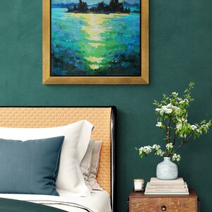 May include: A bedroom interior with a green wall, a bed with a green and white comforter, a nightstand with a vase of white flowers, and a framed painting of a moonlit lake scene.