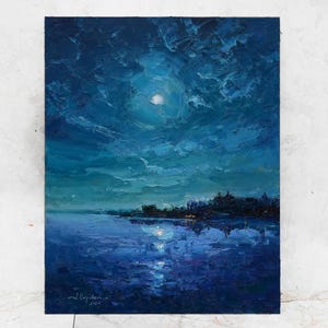 May include: A painting of a dark blue night sky with a full moon and clouds reflected in the water. The water is a dark blue with a light blue reflection of the moon. The sky is a dark blue with white clouds. The painting is signed and dated in the lower right corner.