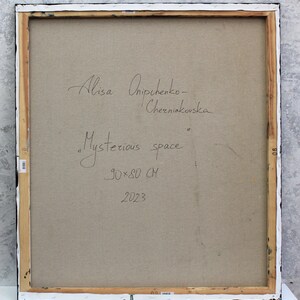 Peut inclure: L'arri&egrave;re d'une toile encadr&eacute;e avec la signature de l'artiste, "Alisa Onischenko-Cherniavska", et le titre, "Mysterious space", &eacute;crits &agrave; l'encre noire. Les dimensions de la peinture sont indiqu&eacute;es comme &eacute;tant "90x80 CM" et l'ann&eacute;e "2023" est &eacute;galement &eacute;crite sur la toile.