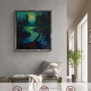 Peut inclure: Une peinture encadr&eacute;e repr&eacute;sentant une sc&egrave;ne de for&ecirc;t &eacute;clair&eacute;e par la lune avec une rivi&egrave;re qui la traverse. La peinture est dans un cadre en bois rustique et est accroch&eacute;e &agrave; un mur gris. La peinture est entour&eacute;e d'un mur gris clair, d'un banc en bois, d'une couverture et d'une plante en pot.