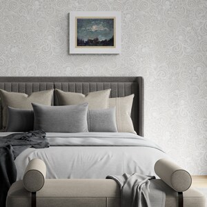 May include: A bedroom scene featuring a bed with a gray headboard, multiple pillows in shades of gray and beige, and a light gray comforter. A framed landscape painting hangs above the bed. The wall is decorated with a light gray, swirling pattern.
