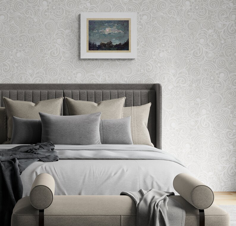May include: A bedroom scene featuring a bed with a gray headboard, multiple pillows in shades of gray and beige, and a light gray comforter. A framed landscape painting hangs above the bed. The wall is decorated with a light gray, swirling pattern.