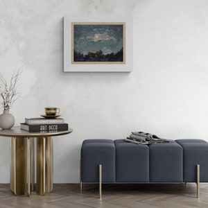 May include: A framed landscape painting depicts a night scene with a moon and trees. A small, round, gold-colored side table holds books, a teacup, and a vase with branches. A blue upholstered bench with gold legs is also present.