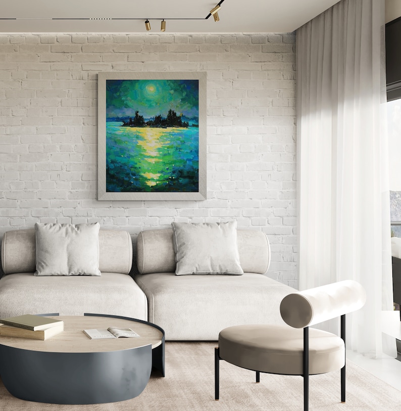 May include: A white brick wall with a framed painting of a moonlit lake scene. The painting is above a white couch with pillows and a round coffee table. A beige chair with a rolled back is in the foreground.