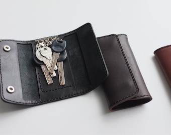 May include: Two leather key holders, one black and one brown, with a set of keys in the black holder.
