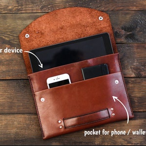 Puede incluir: Bolsa de cuero marrón con una solapa que se abre para revelar un bolsillo para un teléfono o una billetera. La bolsa también tiene un bolsillo más grande para una tableta u otro dispositivo.