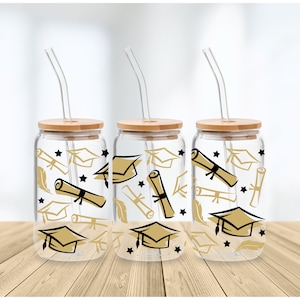 May include: Three clear glass tumblers with bamboo lids and black straws. Each tumbler features a graduation theme with gold and black illustrations of graduation caps, diplomas, stars, and feathers.