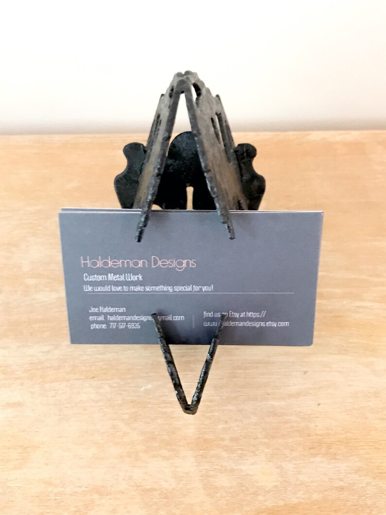 May include: A black metal business card holder with a business card that reads "Haldeman Designs, Custom Metal Work. We would love to make something special for you!" The card also includes contact information for Joe Haldeman.