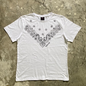 Puede incluir: Camiseta blanca con un diseño negro estilo pañuelo en el pecho. El diseño incluye patrones de cachemira y el texto "NUMBER INK" en la parte inferior. La camiseta tiene mangas cortas y cuello redondo.