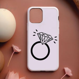Pode incluir: Capa de telefone branca com um design de anel de diamante preto. O anel &eacute; contornado em preto e tem uma forma de diamante no centro.