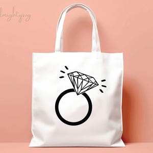 Pode incluir: Sacola branca com um gr&aacute;fico de anel de diamante preto. O anel tem um diamante grande com uma ponta pontiaguda e uma banda simples.
