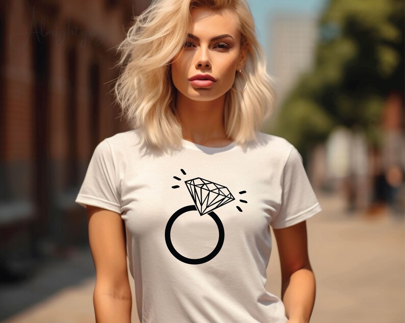 Pode incluir: Camiseta branca com um gr&aacute;fico preto de um anel de diamante. O anel &eacute; estilizado com um design simples e tem um &uacute;nico diamante.