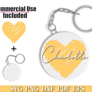 May include: A white circle keychain with a yellow heart design and the name "Charlotte" written in cursive. The keychain is attached to a silver chain and a silver ring.