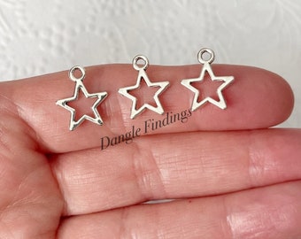 May include: Three silver star-shaped charms with a hole at the top for attaching to jewelry or other crafts. Dangle Findings is printed below the charms.