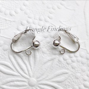 May include: Two silver-toned earring clip-on findings with a small ball at the end of each. The findings are designed to be used with dangle earrings.