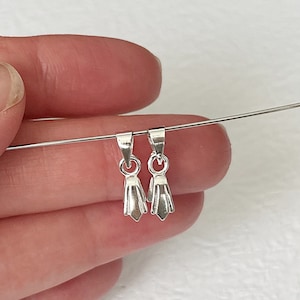 May include: Two silver-toned pendant bails with a pointed, teardrop-shaped design. The bails are hanging from a thin wire.