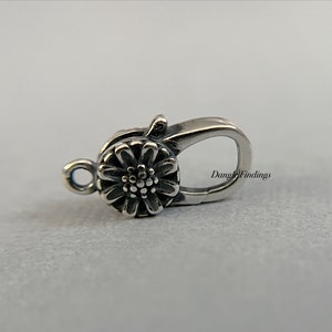 May include: Silver-toned flower clasp with a spring-loaded closure. The clasp is designed to be used for necklaces, bracelets, or other jewelry.