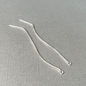 May include: Two silver chain earring extenders. The extenders are made of a delicate chain and have a small loop at the end.