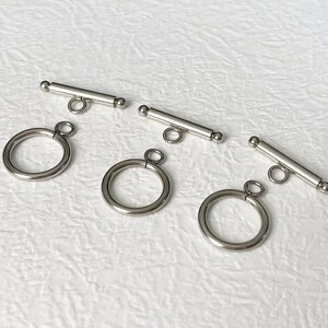 May include: Four silver-toned toggle clasps for jewelry making. Each clasp has a round ring on either end and a straight bar in the middle.