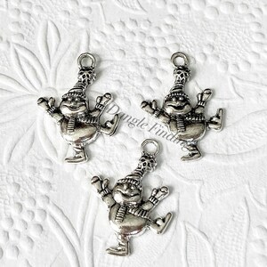 May include: Three silver charm pendants of a snowman ice skating. Each charm has a loop at the top for attaching to a necklace or bracelet.