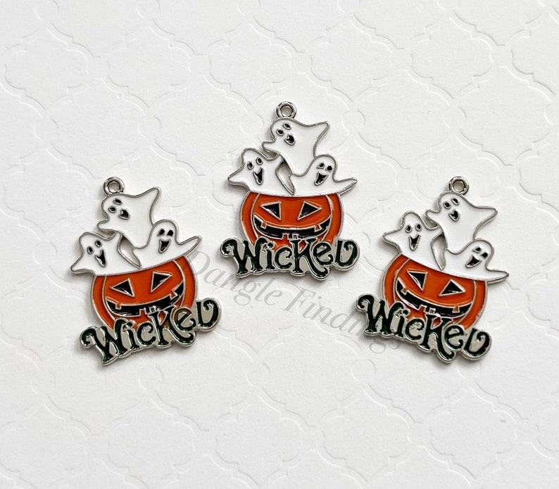 Pode incluir: Tr&ecirc;s pingentes de prata com esmalte laranja e branco. Cada pingente apresenta uma ab&oacute;bora com uma cara de jack-o'-lantern e tr&ecirc;s fantasmas dentro. A palavra "Wicked" est&aacute; escrita em verde abaixo da ab&oacute;bora.