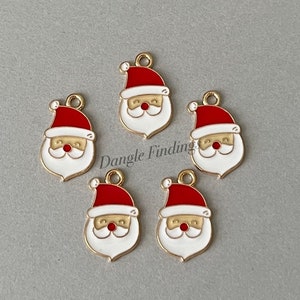 May include: Five gold-colored metal charms featuring a cartoon Santa Claus with a red hat, white beard, and a white face. The charms have a loop at the top for attaching to jewelry or other crafts.