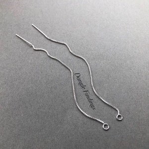 May include: A pair of silver threader earrings with a delicate chain design. The earrings have a wavy pattern and a small loop at the end. The text "Dangle Findings" is visible on the right side of the image.