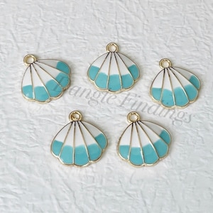 May include: Five gold-tone metal charms shaped like seashells with a white and light blue enamel design.