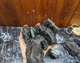 May include: A close-up of a pile of black charcoal rocks, ideal for aquariums or terrariums. The rocks are irregular in shape and have a rough, textured surface.