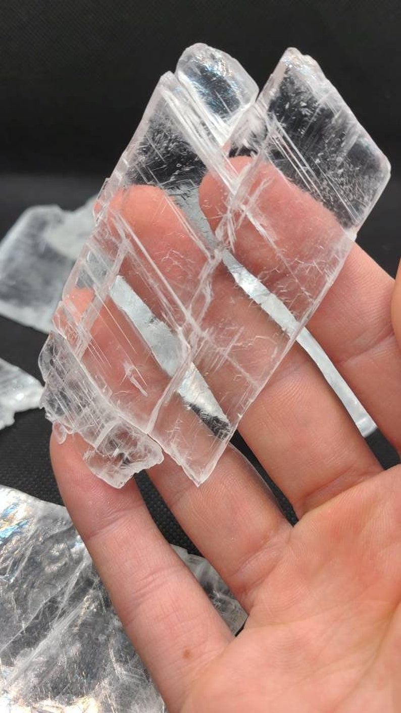 May include: A cluster of clear selenite crystals with a layered, striated texture. The crystals are translucent and have a slight shimmer.
