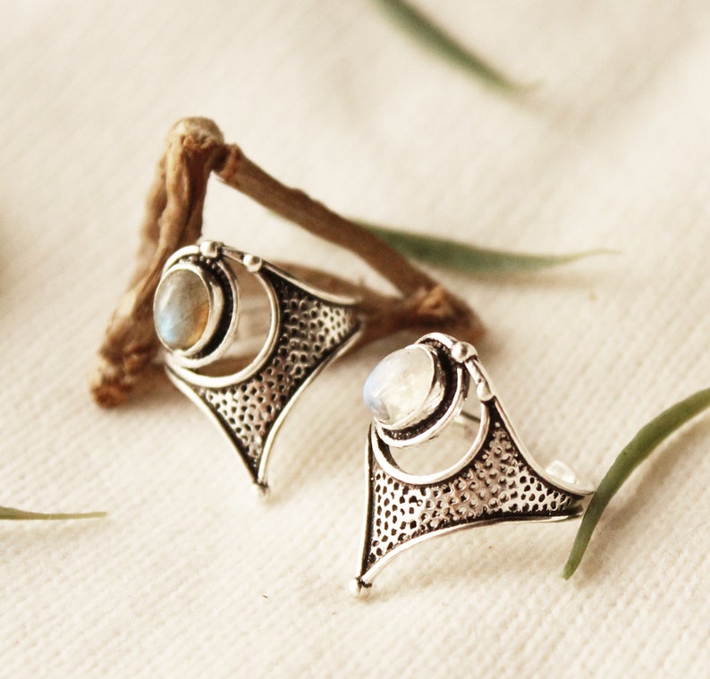 May include: Two silver rings with a delicate, intricate design. Each ring features a round, white gemstone set in a silver bezel.