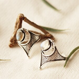 May include: Two silver rings with a delicate, intricate design. Each ring features a round, white gemstone set in a silver bezel.
