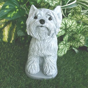 May include: A light gray West Highland White Terrier dog figurine with a textured coat, pointed ears, and a black nose. The sculpture is depicted in a seated position, showcasing detailed fur carvings and a realistic facial expression on a base.