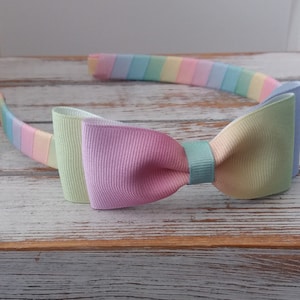 May include: A pastel rainbow headband with a matching bow. The headband is made of a soft, stretchy material and is perfect for adding a touch of color to any outfit.