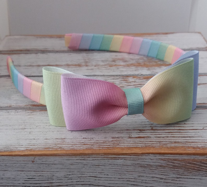 May include: A pastel rainbow headband with a matching bow. The headband is made of a soft, stretchy material and is perfect for adding a touch of color to any outfit.