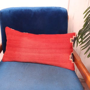 May include: A red and black patterned throw pillow on a blue velvet armchair.