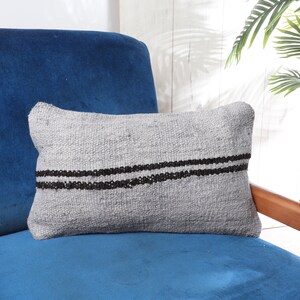 May include: A gray and black striped throw pillow on a blue armchair. The pillow is made of a soft, woven fabric.