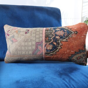 May include: A blue velvet armchair with a patterned throw pillow. The pillow is made of a patchwork of different fabrics, including a beige fabric with a floral pattern, a dark blue fabric with a geometric pattern, and a red fabric with a floral pattern.