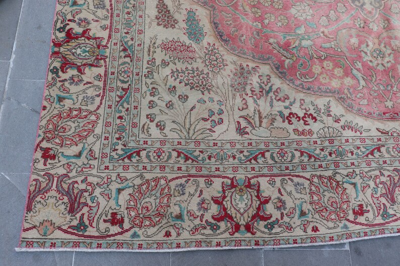Puede incluir: Una alfombra vintage con fondo crema y un medall&oacute;n central en tonos rosa y rojo. La alfombra presenta intrincados patrones florales y geom&eacute;tricos en tonos azul, verde y rojo.