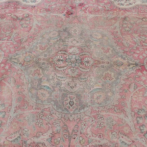 Puede incluir: Una alfombra vintage con un patr&oacute;n floral rosa y gris. La alfombra tiene un medall&oacute;n central con un dise&ntilde;o floral y detalles intrincados.