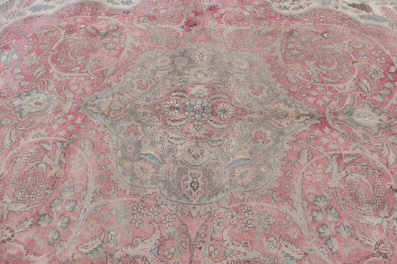 Puede incluir: Una alfombra vintage con un patr&oacute;n floral rosa y gris. La alfombra tiene un medall&oacute;n central con un dise&ntilde;o floral y detalles intrincados.