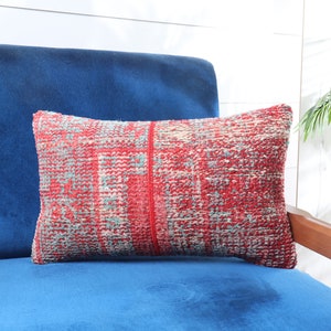 May include: A red, blue, and white patterned throw pillow on a blue velvet armchair.