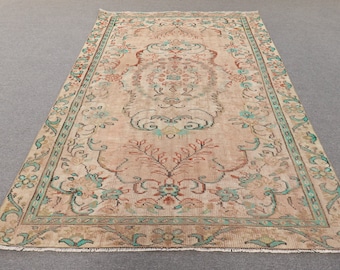 May include: A vintage rug with a beige background and a floral pattern in shades of teal, pink, and red. The rug has a fringed edge.