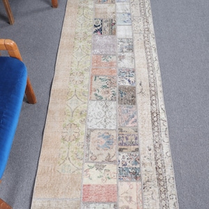May include: A vintage patchwork runner rug with a beige background and a variety of colorful patterns. The rug has a fringed edge and is made of recycled materials.