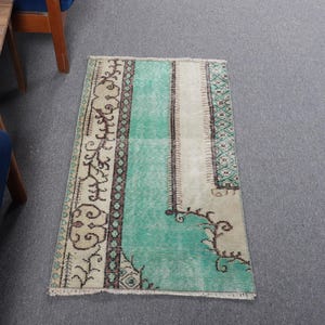 May include: A vintage rug with a light green, cream, and brown color scheme. The rug has a geometric pattern with floral motifs.