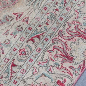 Puede incluir: Una alfombra vintage con fondo crema y intrincados patrones florales en tonos rosa, rojo y azul.